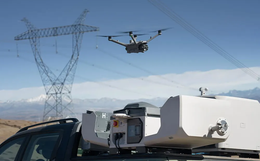 A vehicle-mounted DJI Dock 3 on site under a transmission tower