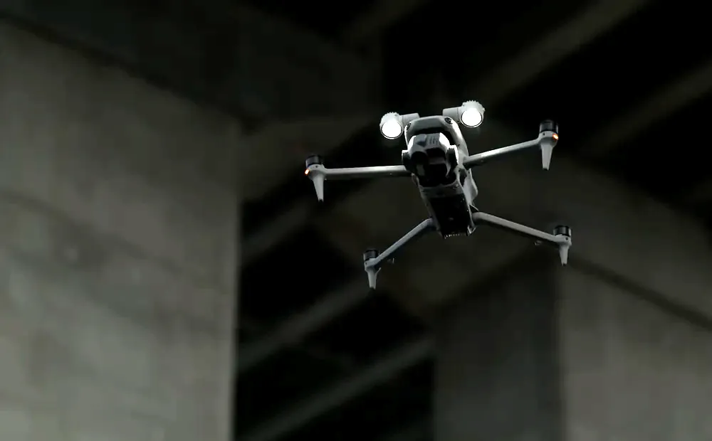 DJI Matrice 4 flying under a concrete structure with its lights on